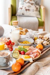 una mesa de desayuno con huevos, carnes, verduras y otros alimentos en Willa Mały Dworek, en Zakopane