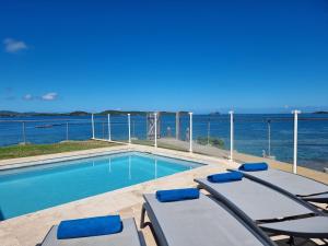 - une piscine avec des chaises et l'océan en arrière-plan dans l'établissement EAST KEYS - Lucy's Bay, à Hyacinthe