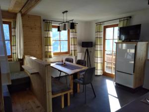 eine Küche mit einem Tisch und einem Kühlschrank sowie einige Fenster in der Unterkunft Martins Comfort Appartement in Assling