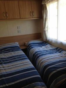 two beds sitting in a room with a window at Static Caravan (Cliburn Station) in Penrith