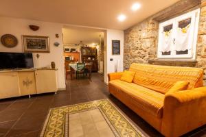a living room with a yellow couch and a kitchen at Appartamento Ai Due Pioppi in Lucca