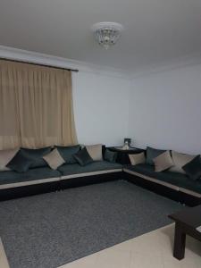 a couch with pillows in a room with a window at Elegant 2-bedroom Tangiers City Appartment with Beautiful Terrace in Tangier