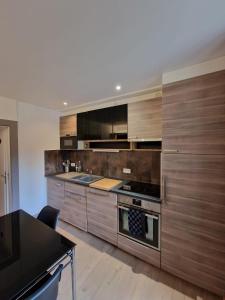 uma cozinha com armários de madeira e um fogão em Appartement 2/4 pers Le Cosy em Lons-le-Saunier