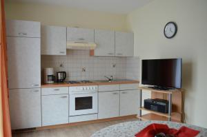 a kitchen with white cabinets and a flat screen tv at Am Randersberg - Wohnung Nr 2 in Grossgmain