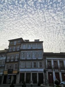 ein großes Gebäude mit weißen Fenstern und einem wolkigen Himmel in der Unterkunft Guimarães Studios Lounge in Guimarães