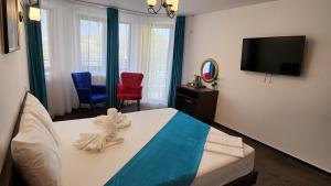 a bedroom with a bed and two chairs and a television at Turquoise Konak in Eforie Sud