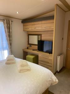 a bedroom with a tv and a bed with towels at Glade 50 Bideford Bay Holiday Park in Bideford