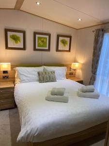 a bedroom with a large white bed with two pillows at Glade 50 Bideford Bay Holiday Park in Bideford