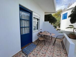 a patio with a blue door and a table and chairs at Anemomilos Studios in Gerani
