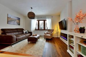 uma sala de estar com um sofá de couro e uma televisão em House Boshanar em Drežnik Grad