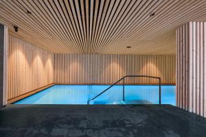 a swimming pool in a building with a wooden wall at Wellness-Sporthotel Ratschings in Racines