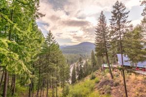 a train traveling through a forest with trees at Das Tree Haus by NW Comfy Cabins in Leavenworth