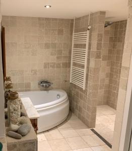 La salle de bains est pourvue d'une baignoire blanche et d'une douche. dans l'établissement Luxury Guest House - Eik aan de dijk, à Aalst