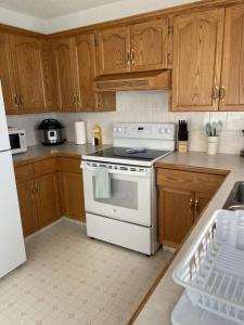 cocina con estufa blanca y armarios de madera en Cozy Home, en Camrose