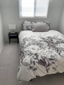 - une chambre avec un lit doté d'une couverture fleurie et d'une fenêtre dans l'établissement Cozy Home, à Camrose