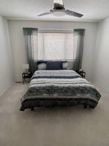 a bedroom with a large bed with a ceiling fan at Cozy Home in Camrose
