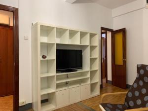 ein Wohnzimmer mit einem TV und weißen Regalen in der Unterkunft Vibes Coruña-Tovar 42 in A Coruña