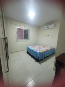 a bedroom with a bed in a white room at Casa para Temporada Praia Grande in Fundão
