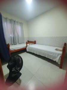 a room with two beds and a fan on the floor at Casa para Temporada Praia Grande in Fundão