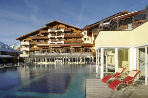 ein Hotel mit einem Pool und zwei Stühlen in der Unterkunft Alpenpark Resort Superior in Seefeld in Tirol