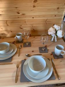 a wooden table with plates and cups and wine glasses at Loch an Eilean Pod Isle of South Uist in Pollachar +50 photos