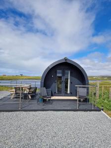 a circular building with a table and chairs in front of a lake at Loch an Eilean Pod Isle of South Uist in Pollachar