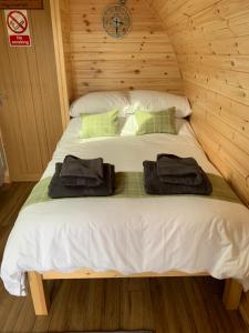 Una cama en una cabaña de madera con dos toallas. en Loch an Eilean Pod Isle of South Uist en Pollachar