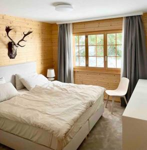 a bedroom with a bed and a chair and windows at Apartment with stunning view! Ski-in, ski-out in Villars-sur-Ollon