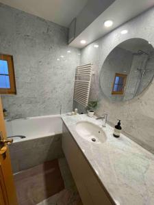 a bathroom with a sink and a tub and a mirror at Apartment with stunning view! Ski-in, ski-out in Villars-sur-Ollon