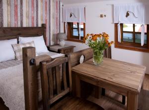 um quarto com uma cama e uma mesa com um vaso de flores em Penzion Jízdárna Hejtmánkovice em Broumov