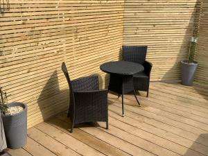 three chairs and a table on a patio at Beauslodge Authentic Log Cabin With Private Hot Tub in Arford