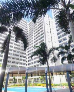 un grand bâtiment avec des palmiers devant lui dans l'établissement Modern Brand New Condo in Grace Residence Taguig, à Manille