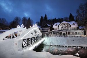 eine Brücke über einen Fluss vor einem Gebäude in der Unterkunft Apartment Na Skále CLOSE TO CITY CENTER & SKI LIFT in Špindlerův Mlýn