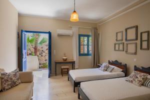 een hotelkamer met 2 bedden en een bank bij The Boathouse Hotel in Kamari