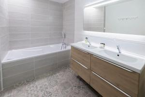 ein Badezimmer mit einer Wanne und einem Waschbecken und einer Wanne und einer Badewanne in der Unterkunft Le Familial - Tout équipé - Proche centre in Montluçon