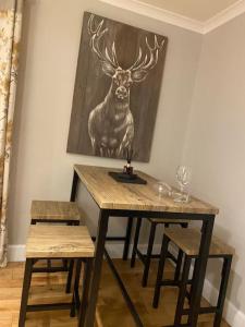 un tavolo in legno con due sedie e una foto di un cervo di Neptune's Apartment a Fort William