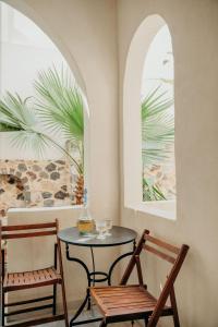 een tafel en twee stoelen in een kamer met twee ramen bij The Boathouse Hotel in Kamari