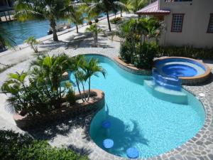 a swimming pool in a resort with palm trees at Placencia Pointe Townhomes #5 in Placencia Village