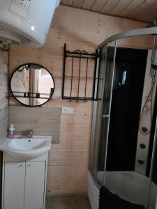 a bathroom with a sink and a shower and a mirror at Domki Tręby Stare in Tręby
