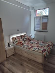 een slaapkamer met een bed met een dekbed en een raam bij Szare Miraże in Busko-Zdrój