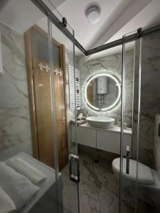 y baño con ducha, lavabo y espejo. en Jahorina Apartman Benvenuti en Jahorina