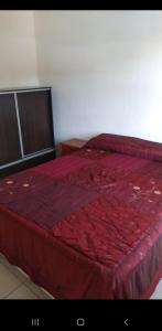 Una cama roja con un edredón rojo encima. en Departamentos San Rafael en San Rafael
