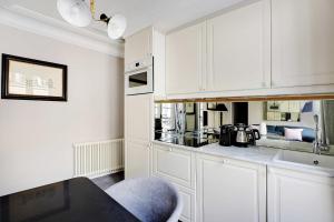 a kitchen with white cabinets and a blue chair at Magnifique appartement 4P- Musée du Louvre Tuileries in Paris