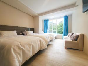 a bedroom with two beds and a chair and a window at Xperience Hotel Ec in Baños