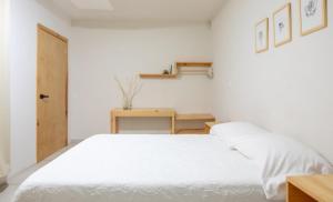 een slaapkamer met een wit bed en een houten tafel bij Casa Matia in Guadalajara