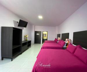 a room with three beds with pink sheets and a tv at Hotel Maricela in San Juan de los Lagos