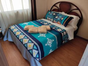 ein Bett mit einer blauen Decke und zwei Holzscheiten in der Unterkunft Dulce Hogar in Loja