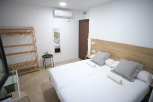 1 dormitorio con 1 cama blanca grande y 2 almohadas en Urban Rooms Alicante, en Alicante