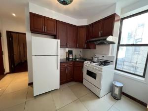 a kitchen with wooden cabinets and a white refrigerator at Antique Victorian 2 Bedroom best Location in New York