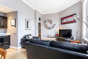 ein Wohnzimmer mit einem schwarzen Ledersofa in der Unterkunft Chic Farringdon Flat in London